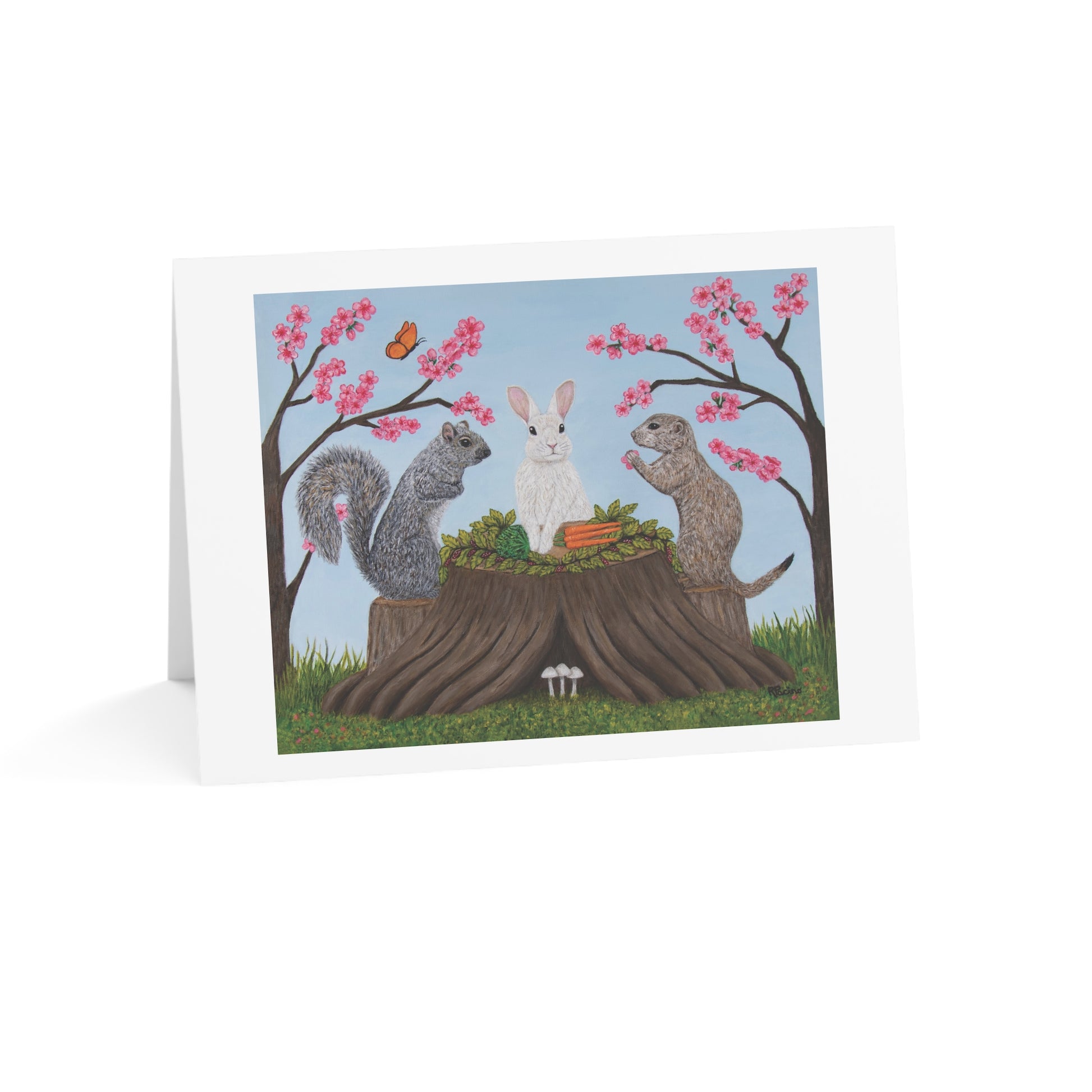 A white greeting card standing upright on a white surface, featuring an illustrated woodland scene with a gray squirrel, a white rabbit, a groundhog, pink cherry blossoms, and a butterfly.
