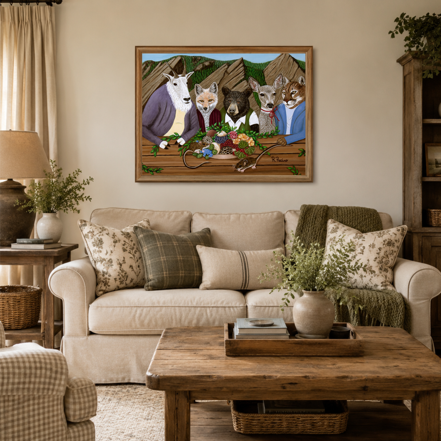 A framed art print depicting anthropomorphic wildlife at a picnic hanging on a beige wall above a cream sofa in a styled living room.