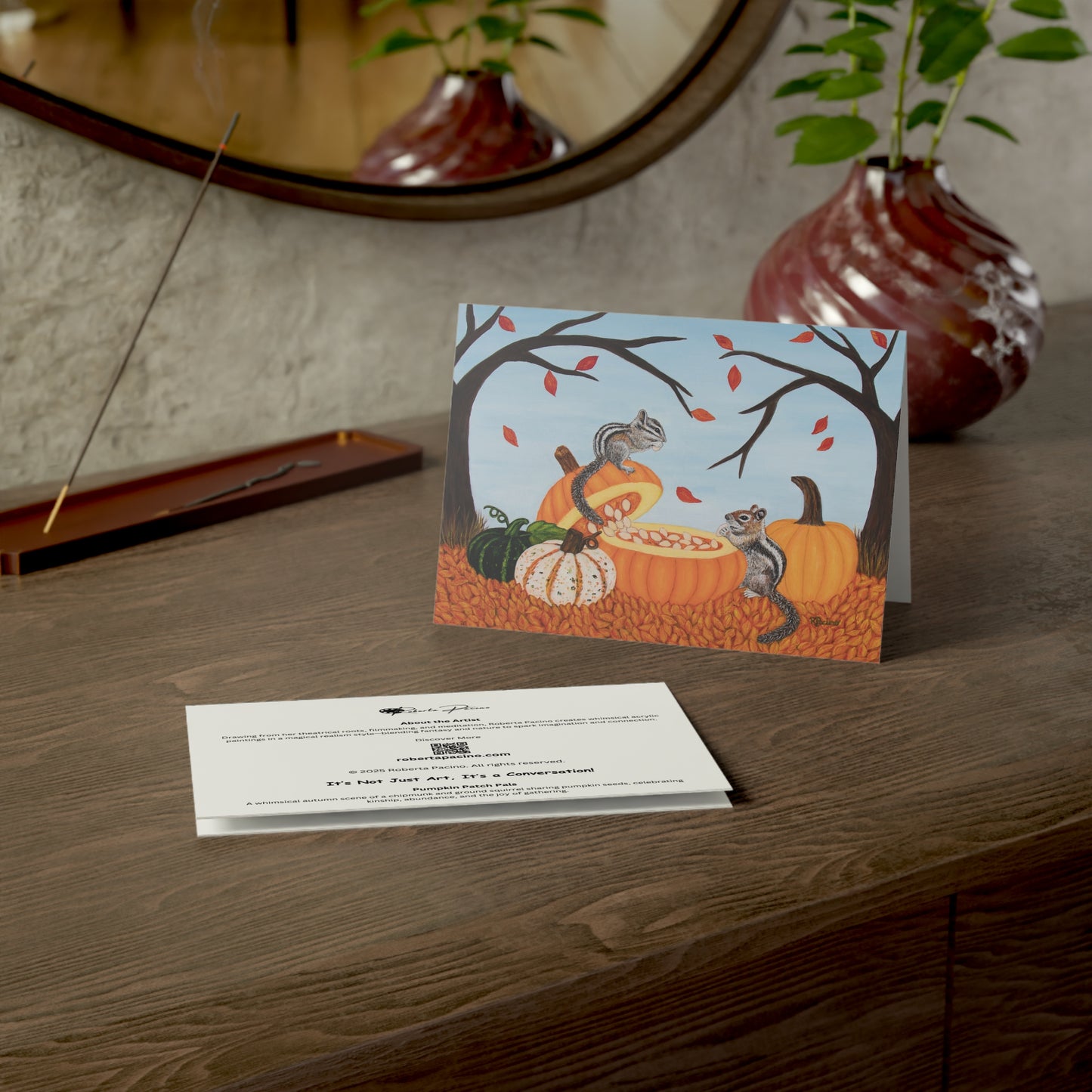 Autumn-themed greeting card with pumpkins and squirrels on a wooden surface by Roberta Pacino.