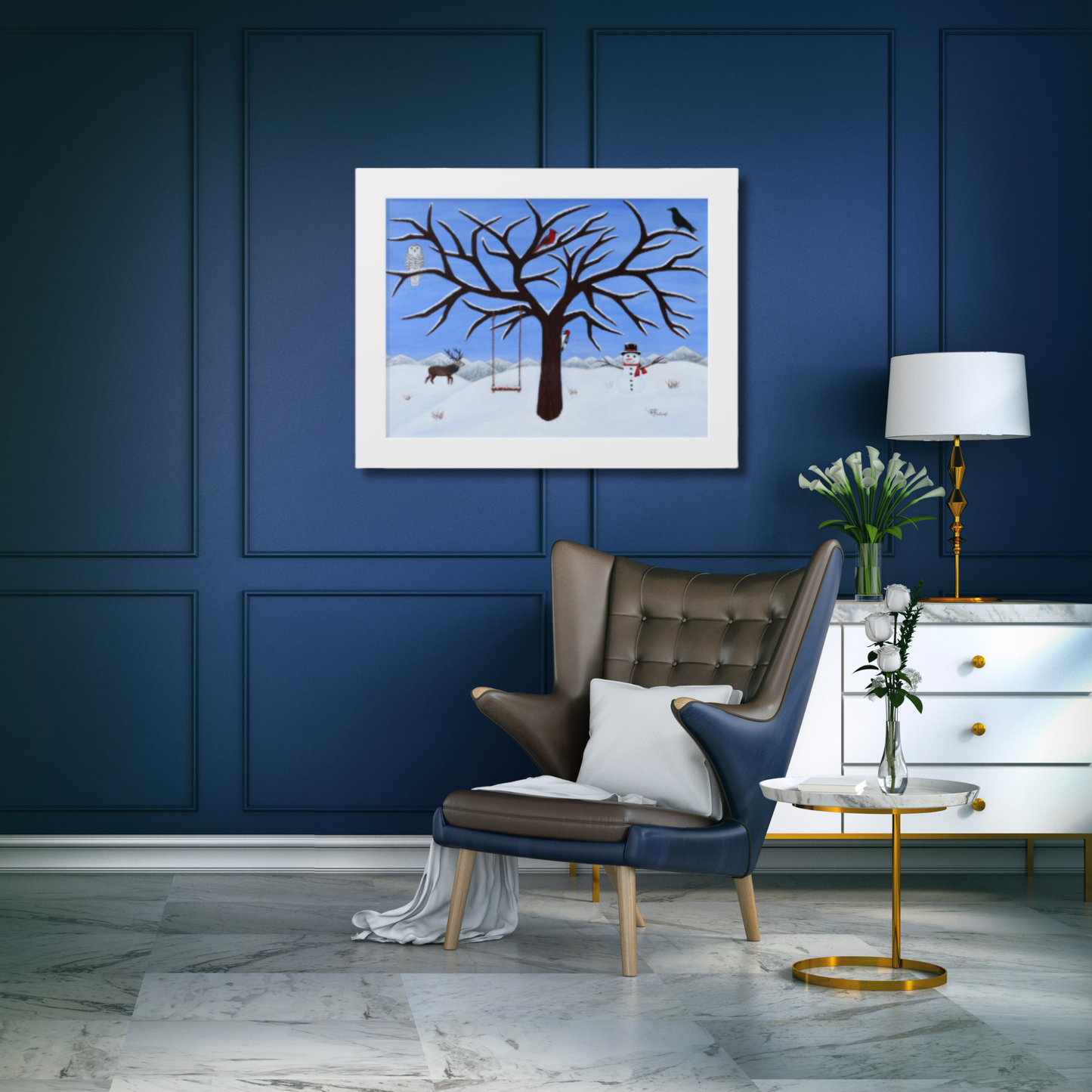 A framed art print depicting a winter tree scene with birds and deer, displayed on a dark blue paneled wall above a brown leather armchair in a styled room.