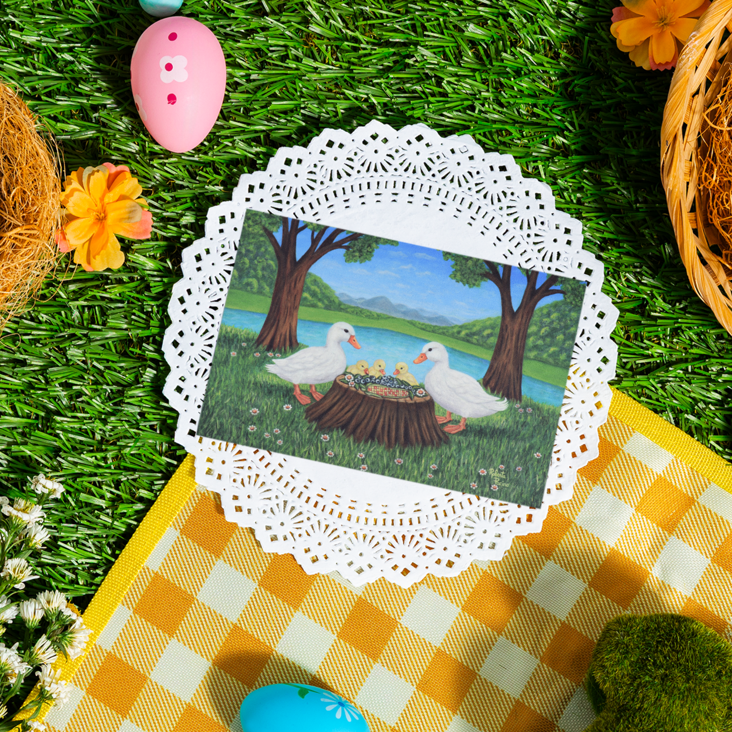 Sunlit Supper greeting card featuring two white ducks and three ducklings sharing a meal beside a pond in a sunny park setting, from original art by Roberta Pacino