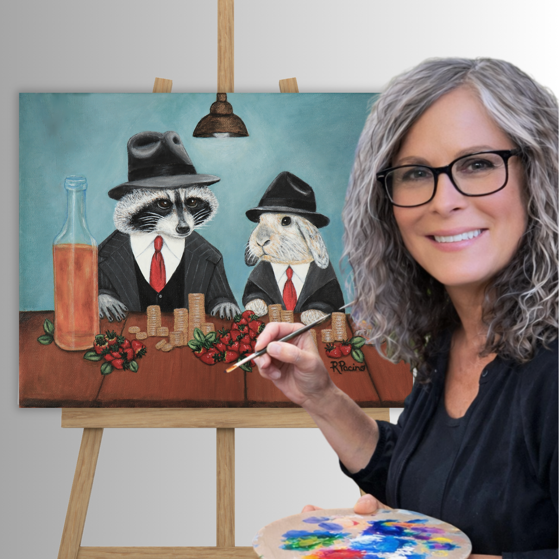 Roberta Pacino holds a paint palette in front of a canvas painting on an easel. Her Sweet Deal painting depicts two dressed-up raccoons and a rabbit sitting at a table with chips, strawberries, and a bottle against a teal background.
