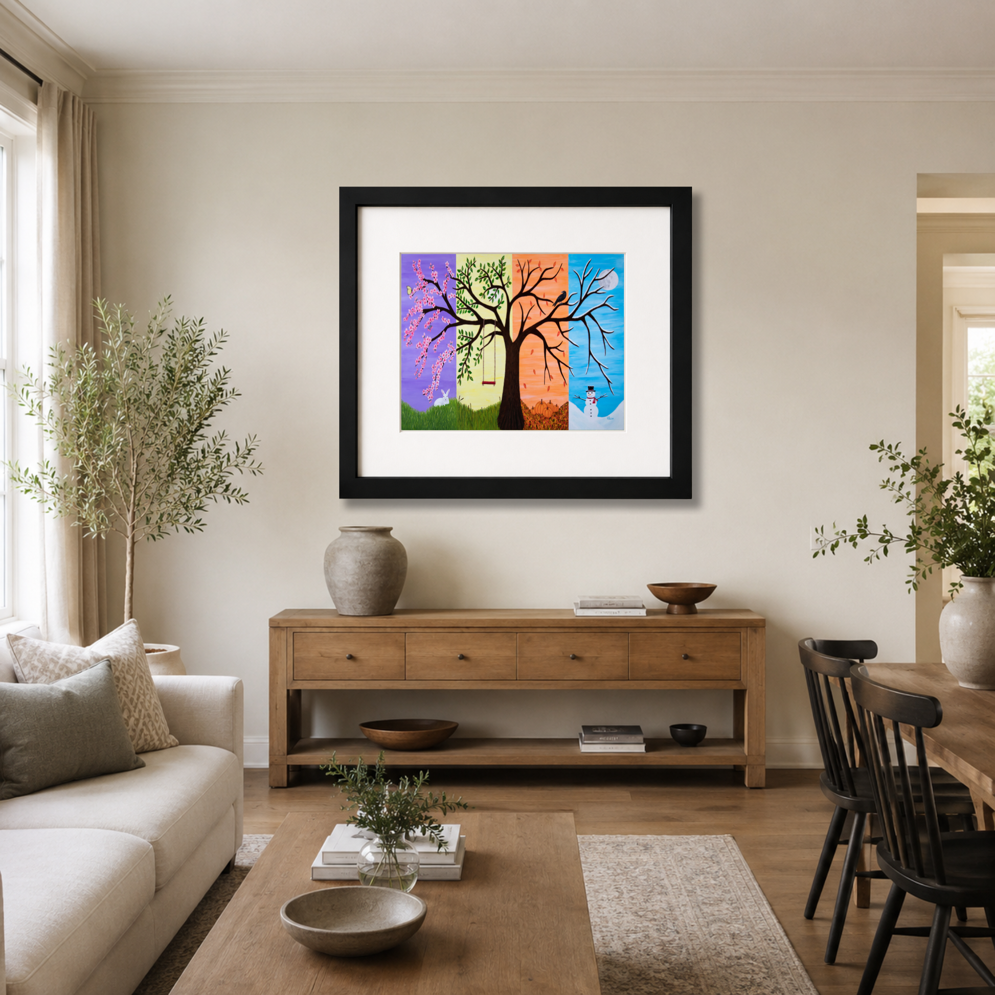 A framed  Tree of Life art print by Roberta Pacino, depicting a stylized tree with colorful seasonal sections (purple, green, orange, blue) hanging on a beige wall in a modern living room setting.